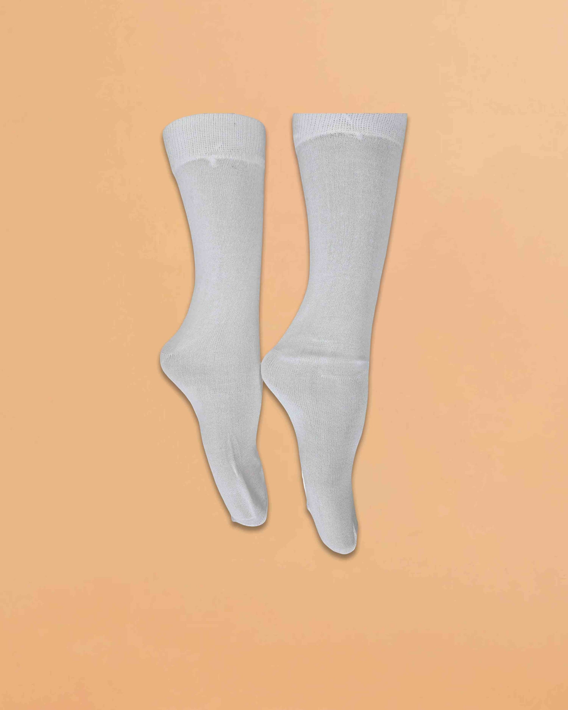 Ambika Stores pair of plain white full-length organic combed cotton school socks on a light orange background