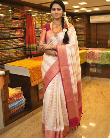 Ambika Stores white silk saree with intricate peach paisley motifs and a contrasting border, perfect for festive occasions.